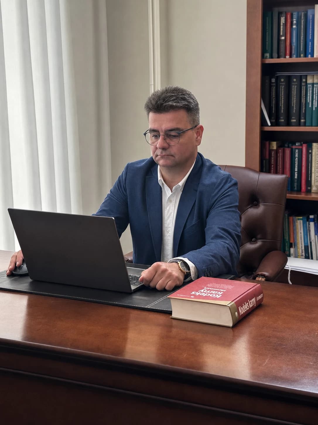 Adwokat Jacek Kozłowski pracujący przy biurku w kancelarii w Toruniu